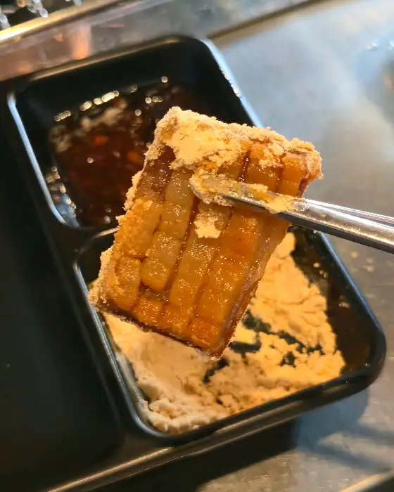 집게로 집혀 올려진 껍데기 조각에 콩가루가 묻어 있는 모습