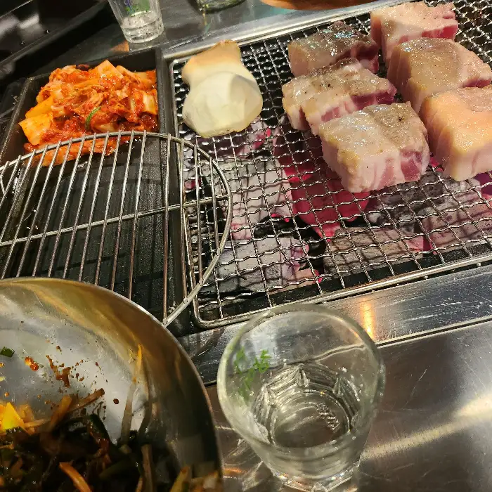고기와 곁들임 반찬, 그리고 술잔이 놓인 테이블 풍경