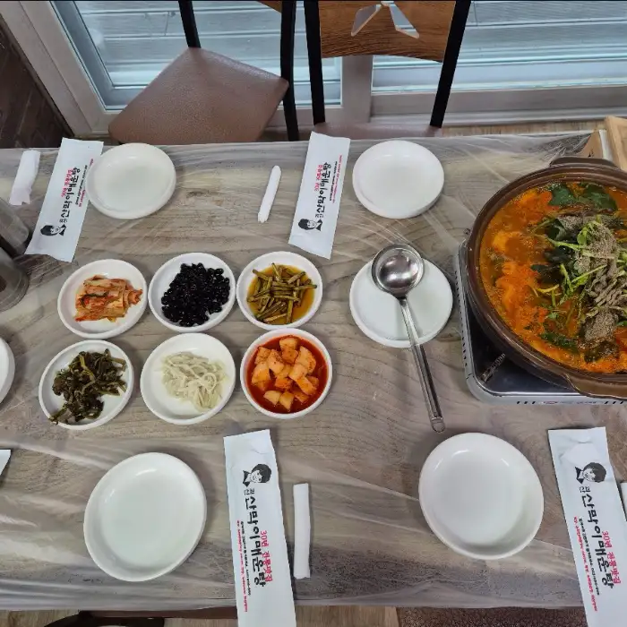 테이블에 차려진 다양한 반찬들과 냄비에 끓고 있는 매운탕