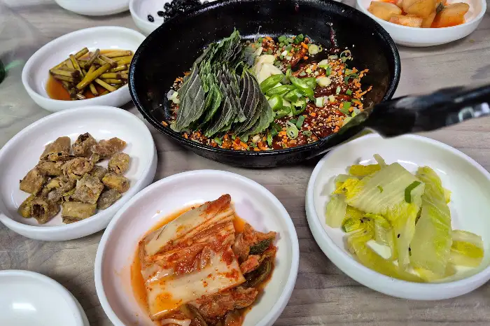 김치, 젓갈, 채소 반찬 등이 담긴 작은 그릇들과 중앙의 볶음 요리