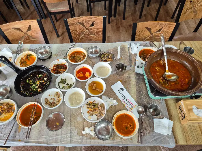 다양한 반찬들과 끓고 있는 매운탕 냄비, 그리고 덜어 먹을 앞접시