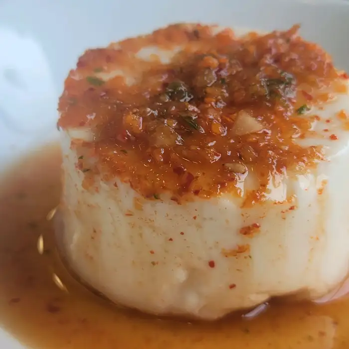 접시에 담긴 하얀 순두부 요리, 위에 양념장이 올라가 있다