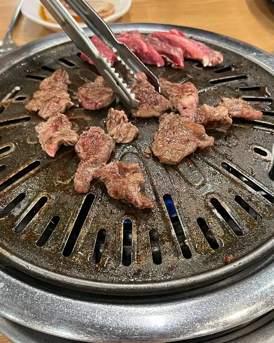 불판 위에서 구워지는 고기와 곁들임 메뉴