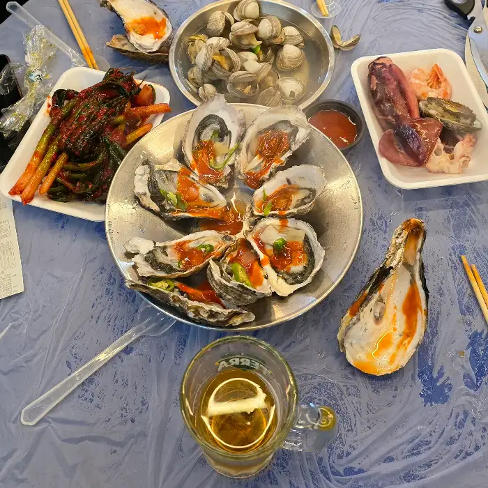 다양한 해산물 요리가 차려진 테이블, 싱싱한 굴과 꼬막, 그리고 해산물 모둠