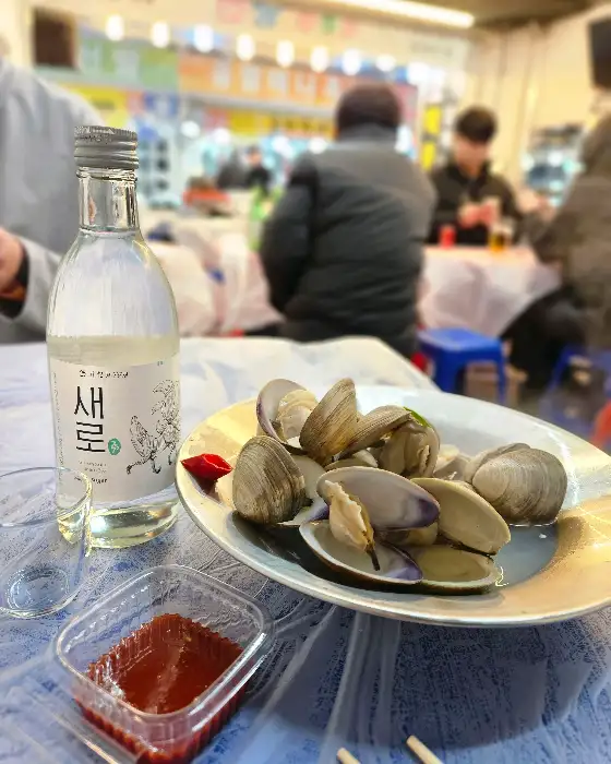 소주 한 병과 신선한 조개류가 담긴 접시