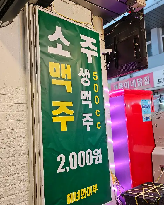녹색 천에 '주류 2000원'이라는 글씨가 크게 쓰여진 간판