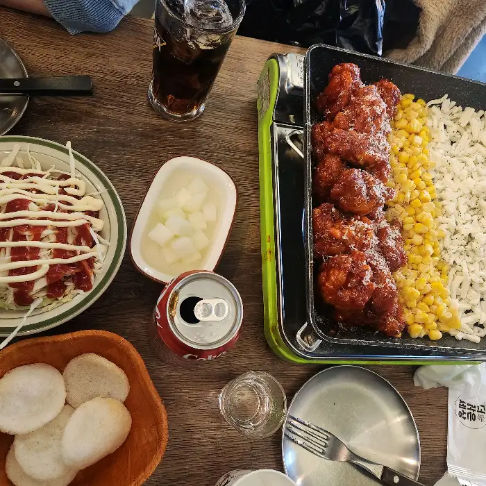 테이블에 놓인 치킨, 옥수수, 샐러드, 음료 등