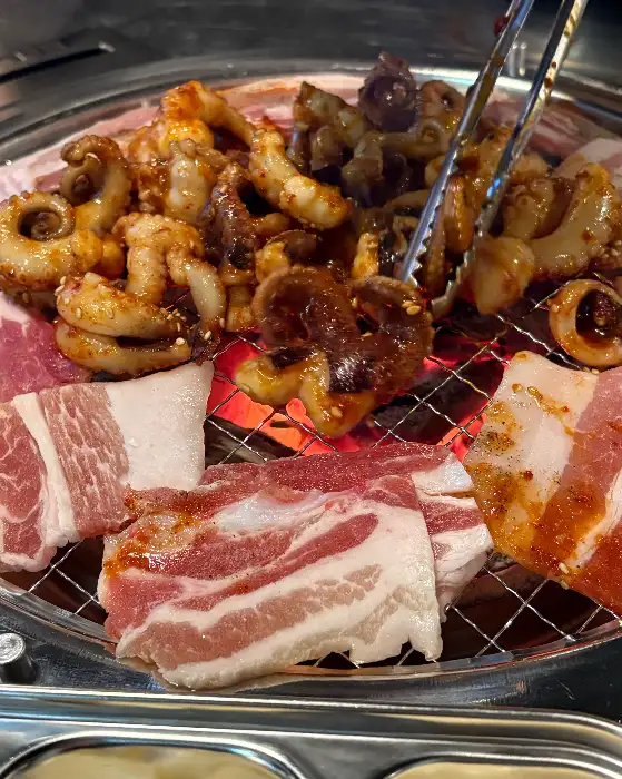 집게로 숯불 위 쭈꾸미를 뒤집는 모습