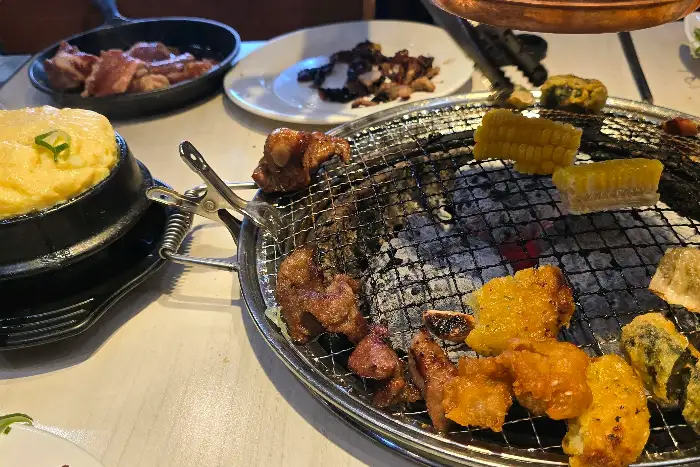 숯불 위에 구워지는 다양한 고기와 옥수수