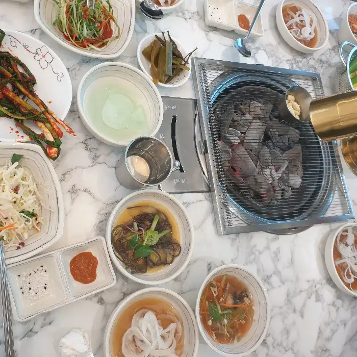 다양한 고기와 찌개, 반찬이 한상 가득 차려진 모습