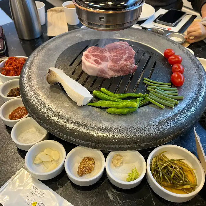 두툼한 목살 한 덩이가 숯불 위에서 익어가는 모습