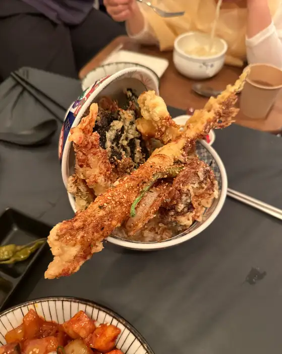 푸짐하게 담긴 텐동의 모습, 새우, 가지, 연근 등 다양한 튀김이 먹음직스럽게 올려져 있다.