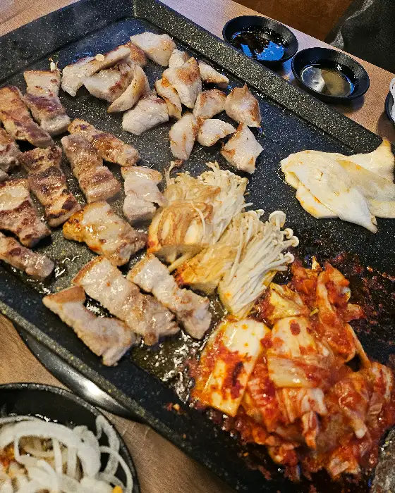 불판 위에 구워지는 다양한 부위의 고기와 김치