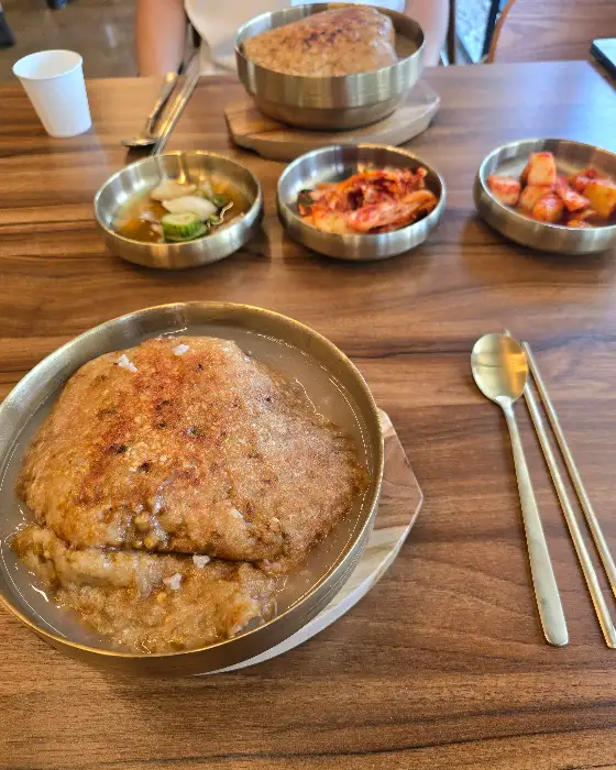 테이블 위에 놓인 누룽지 삼계탕과 곁들임 반찬들