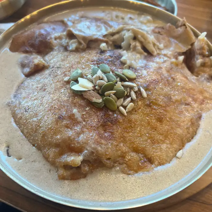 누룽지 위에 고명으로 올려진 씨앗과 삼계탕 모습