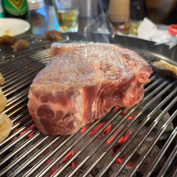 두툼한 오겹살 덩어리가 숯불 위에서 익어가는 모습