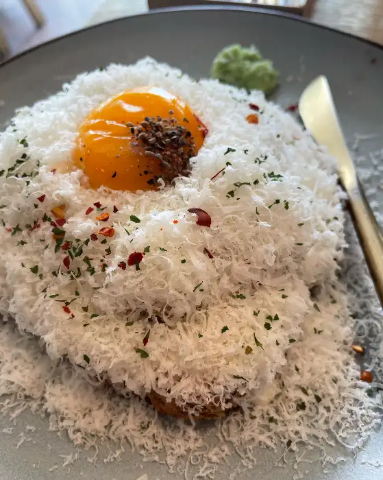 노른자가 올라간 파스타 위에 치즈가 듬뿍 뿌려진 사진