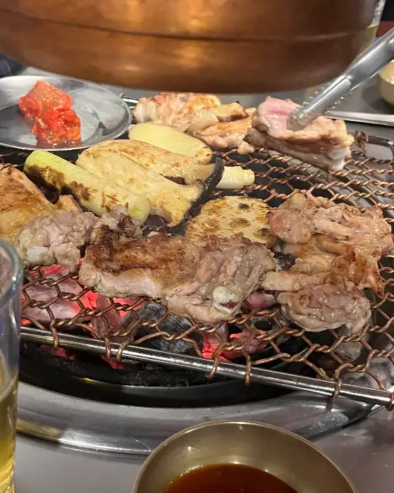 잘 구워진 닭갈비 조각들을 집게로 집고 있는 모습