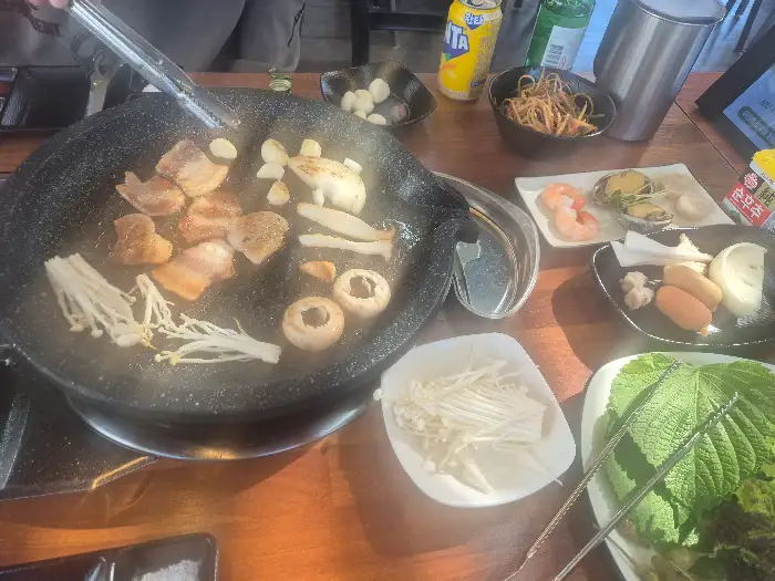불판 위에서 익어가는 삼겹살과 버섯, 마늘
