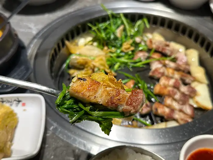숯불 위에서 구워지는 삼겹살과 미나리, 백김치