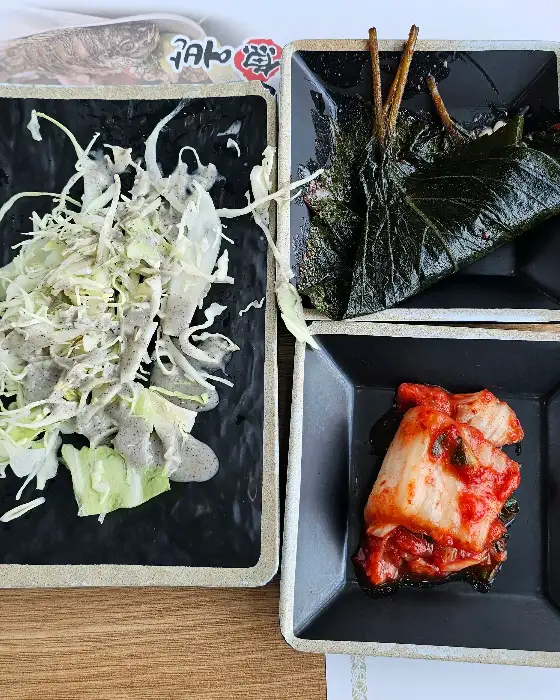 접시에 담긴 샐러드, 깻잎 장아찌, 김치 등의 밑반찬 모습