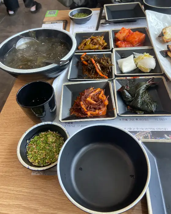 식탁 위에 놓인 미역국, 밥그릇, 컵, 그리고 여러 가지 밑반찬이 담긴 작은 접시들