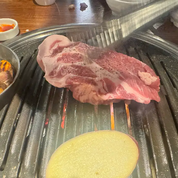 테이블 위에 놓인 생고기와 굽기 시작한 고기