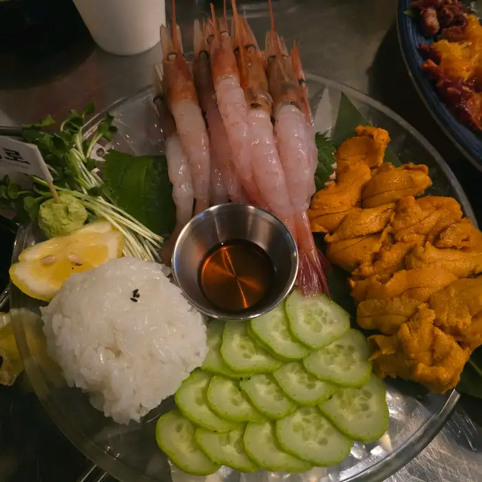 신선한 새우, 단새우, 우니, 레몬, 오이 등이 담긴 플레이트