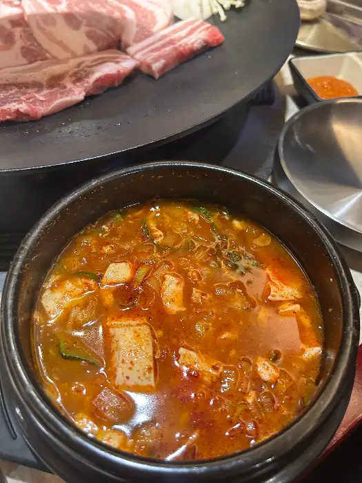 솥뚜껑 위에서 맛있게 구워지고 있는 삼겹살과 김치