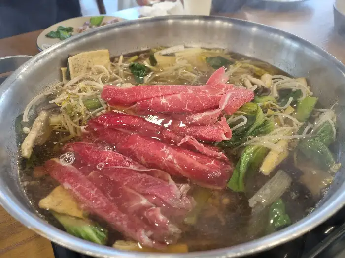 끓는 샤브샤브 냄비 안에는 고기, 채소, 면 등이 들어 있다.