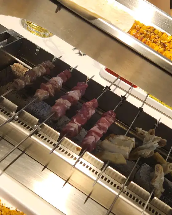 숯불 위에서 익어가는 다양한 꼬치와 곁들임 메뉴