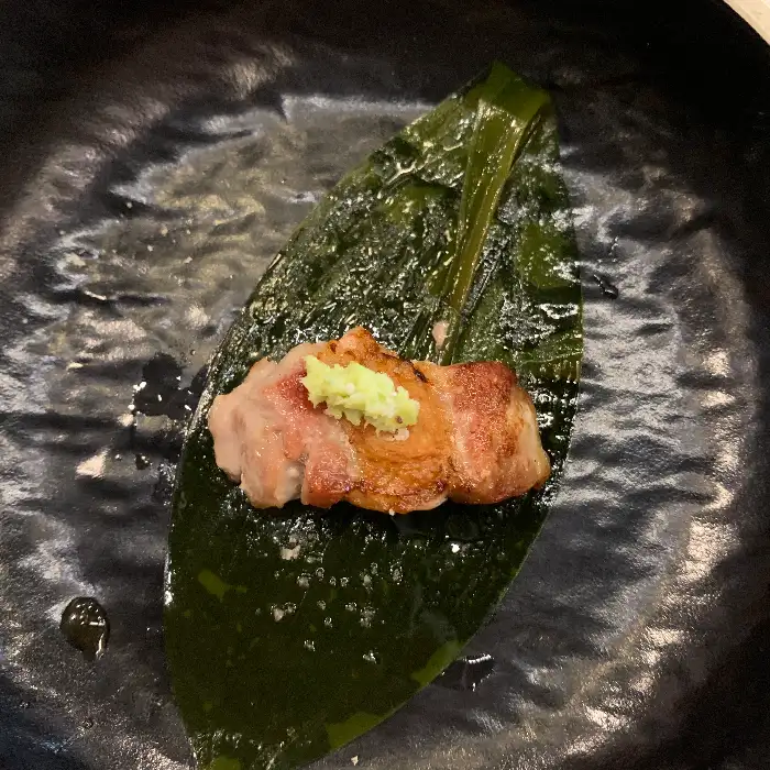 명이나물 위에 올려진 고기 한 점과 와사비