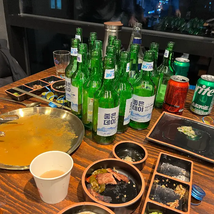 불판 위에서 익어가는 고기와 술병들