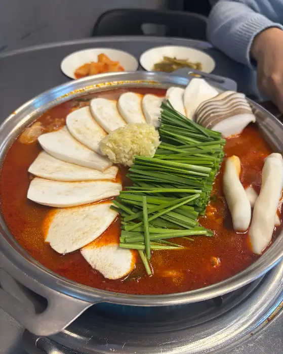 닭도리탕 위에 대창, 버섯, 파, 떡 등이 푸짐하게 올라가 있고, 국물이 진하게 보인다.