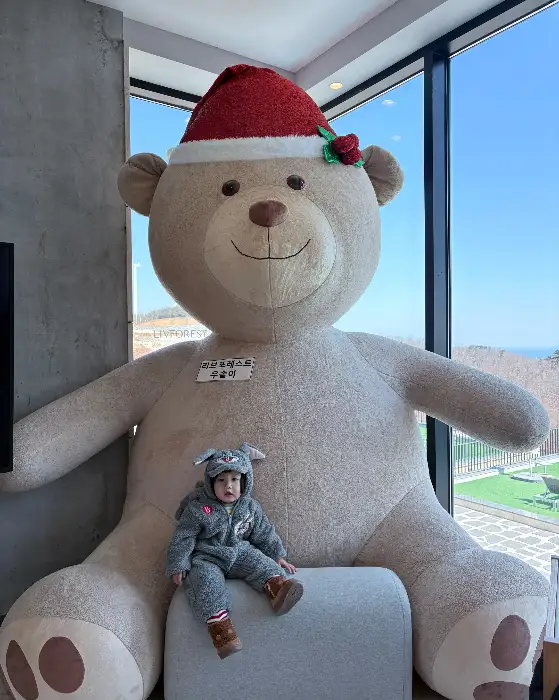 크리스마스 모자를 쓴 대형 곰인형과 아이