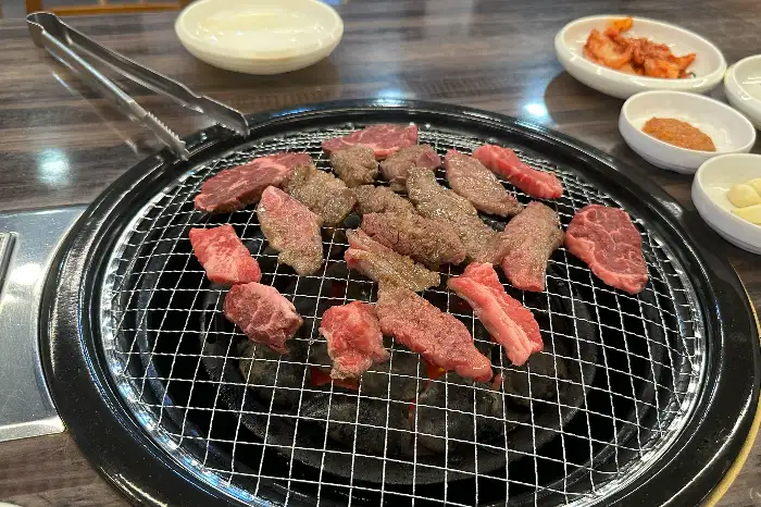 숯불 위에서 익어가는 소고기와 다양한 곁들임 반찬