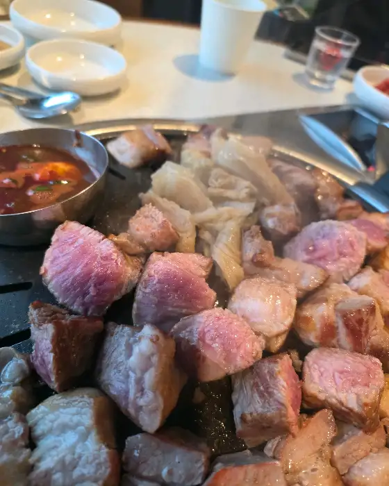 잘 구워진 흑돼지 고기 덩어리가 불판 위에 놓여 있는 모습