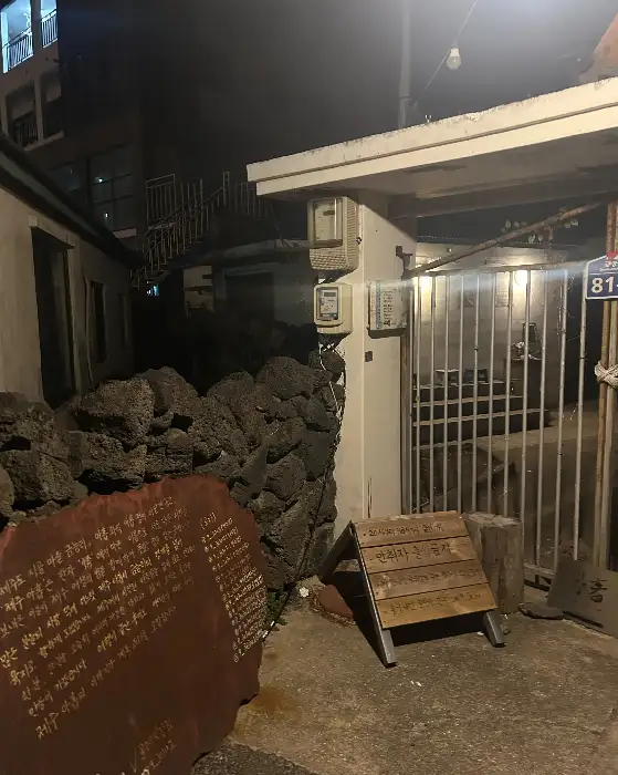 어두운 밤, 제주도의 돌담과 대문이 보이는 골목길의 풍경입니다.