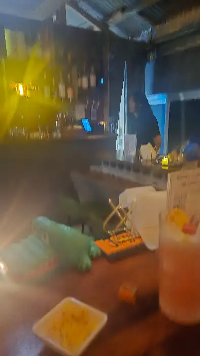 바 안에서 칵테일 잔과 여러 소품들이 보이고, 배경에는 바텐더가 서 있습니다.