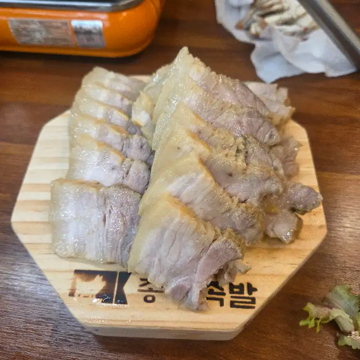 먹음직스럽게 썰린 보쌈 한 점, 쌈 채소와 함께 놓인 모습