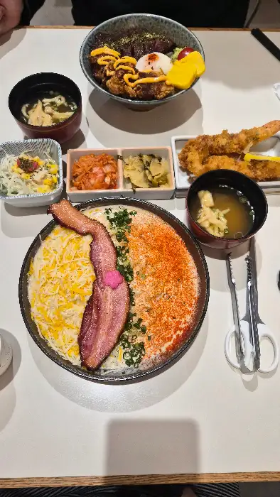 다양한 일식 메뉴가 식탁 위에 차려진 모습, 덮밥, 튀김, 샐러드, 국 등이 보인다.