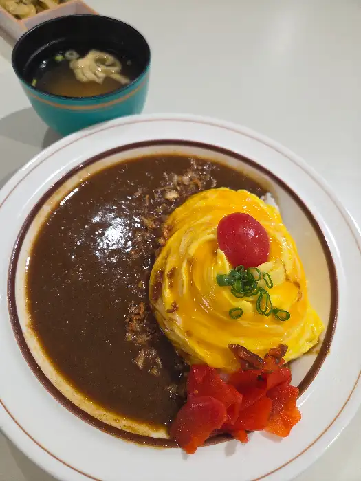 오믈렛 카레, 부드러운 오믈렛 위에 귀여운 방울토마토와 파가 올라가 있고, 곁들임으로 붉은 피클이 보인다.
