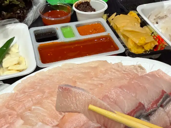 여러 가지 소스와 쌈 채소, 마늘, 고추, 그리고 신선한 회가 담긴 접시