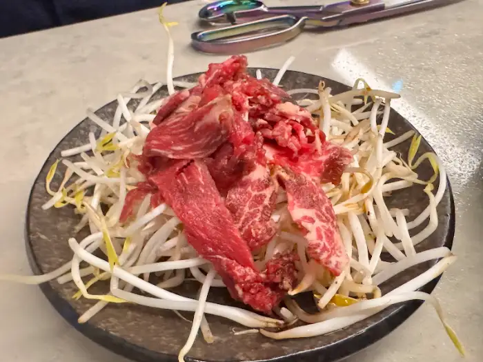 신선한 콩나물 위에 얇게 썬 생고기가 올려진 플레이트