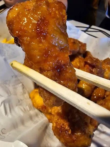 집게로 집어든 먹음직스러운 치킨 조각