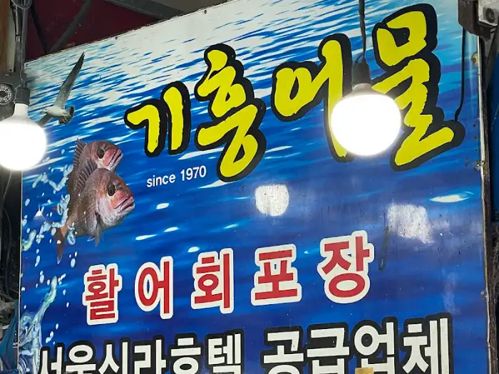 테이블에 놓인 다양한 해산물과 곁들임 음식들. 술병, 쌈 채소, 생선회 등이 보인다.