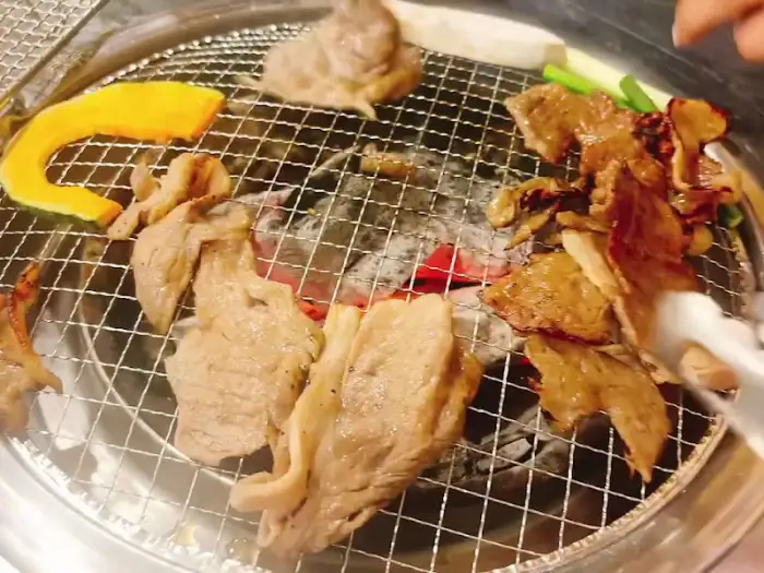 숯불 위에서 여러 가지 재료와 함께 구워지는 돼지고기