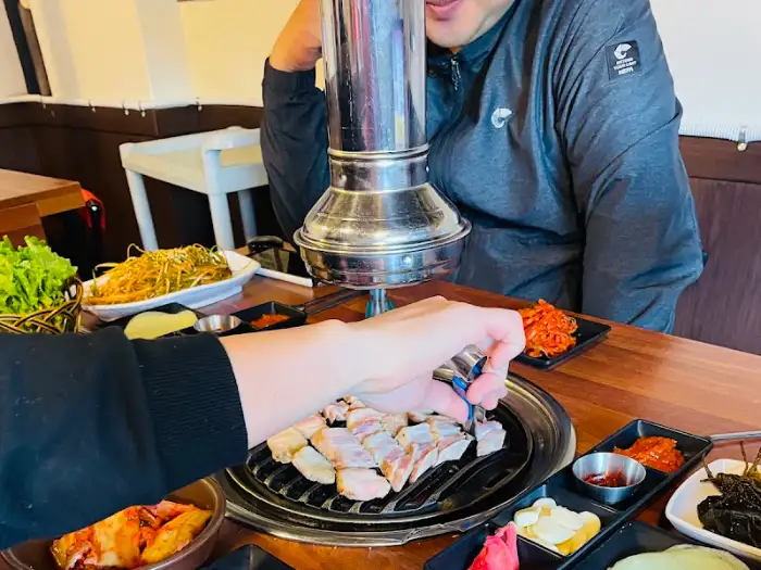 직원이 숯불 위 고기를 집게로 집어 익히는 모습