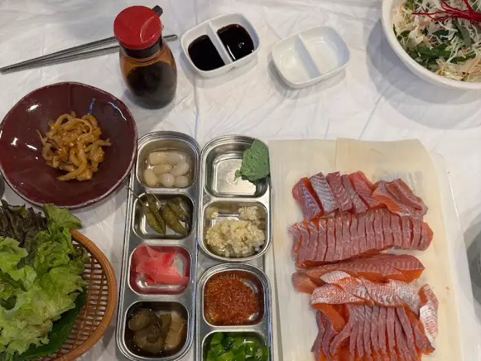 테이블에 차려진 민물회 한 상차림의 모습, 쌈 채소, 회, 곁들임 반찬 등이 보인다.