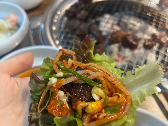 상추 위에 콩나물 무침과 고기를 얹어 싸 먹는 모습